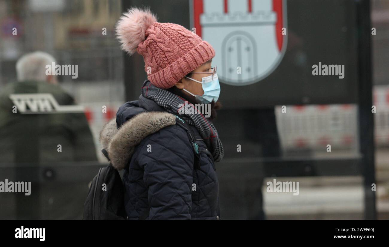 Eine Frau geht mit einer Mund-Nasen-Maske eine Straße entlang. St. Georg Hamburg *** Eine Frau mit Mund- und Nasenmaske läuft auf einer Straße in St. Georg Hamburg Stockfoto