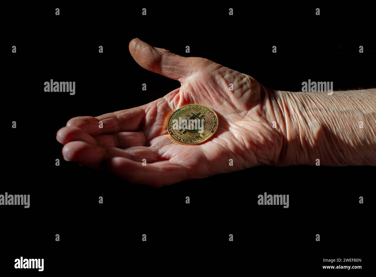 bitcoin-Münze in der Hand einer alten Frau Stockfoto