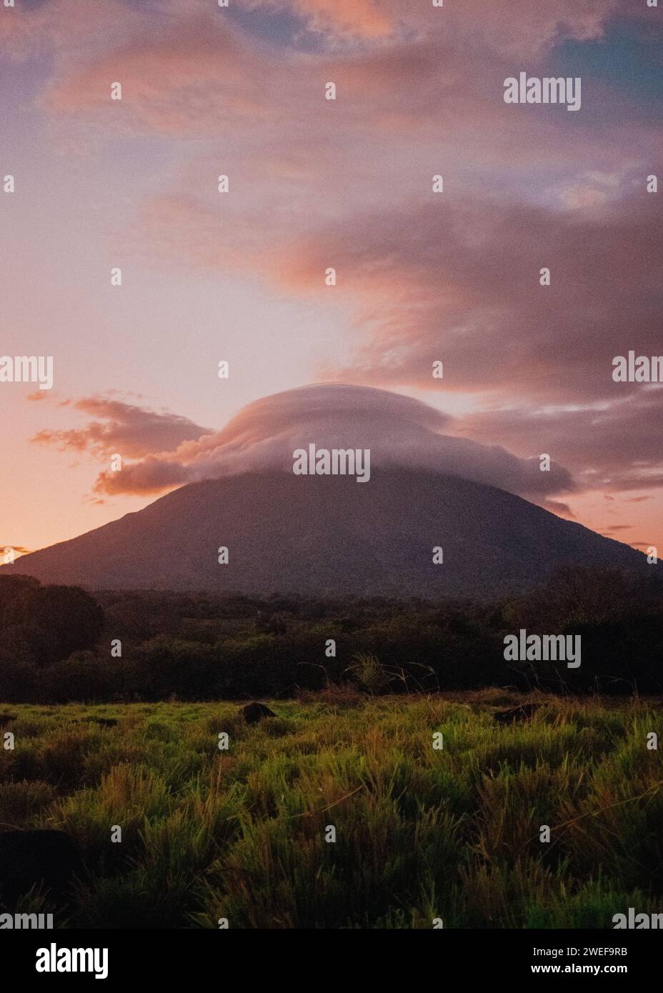 Eine weiche Wolke, die während eines Sonnenuntergangs auf einem Vulkan sitzt Stockfoto