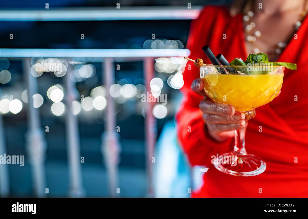 Frau in rotem Kleid trinkt Mango-Daiquiri-Cocktail. Stockfoto