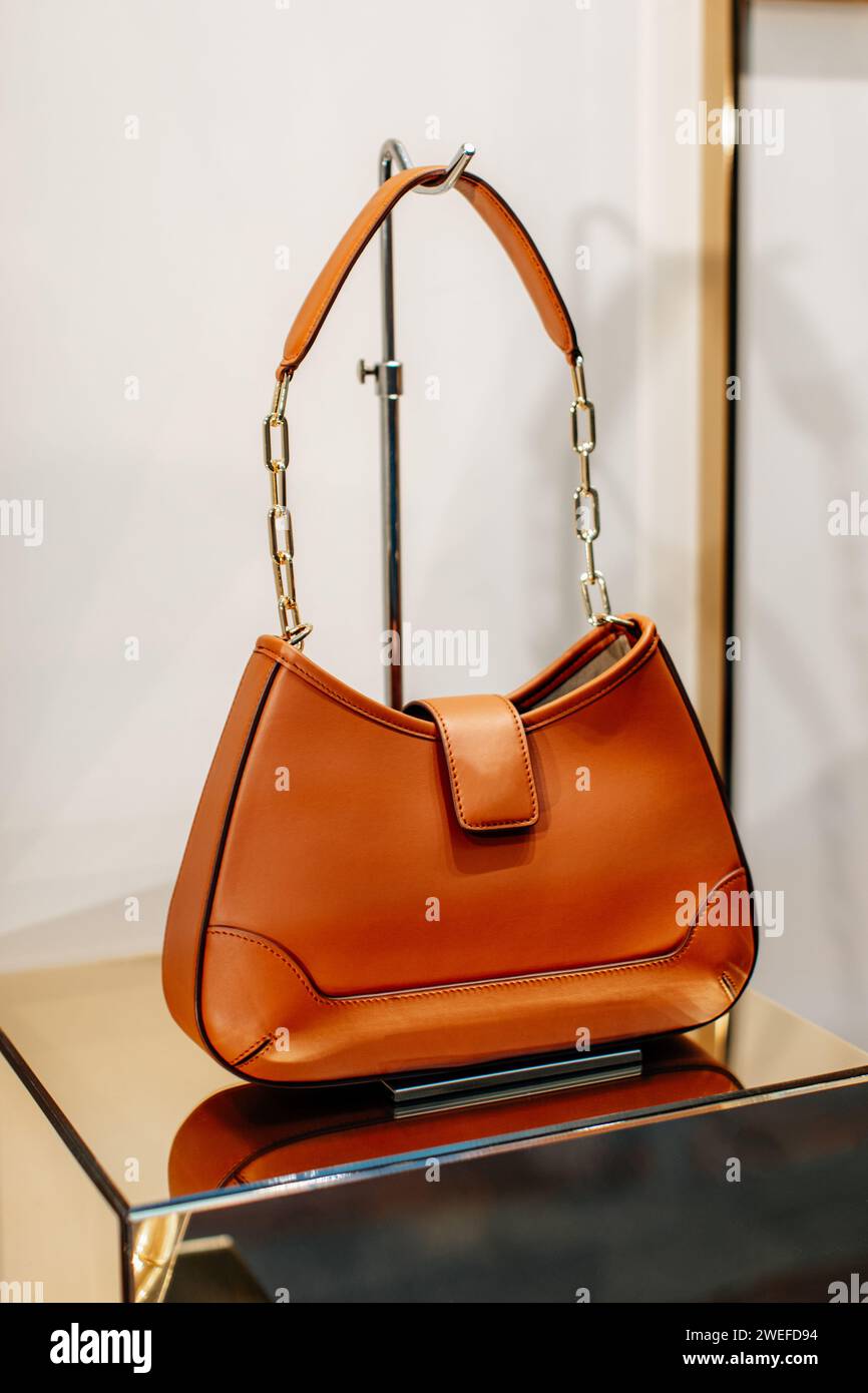 Hellorange Damen-Handtasche aus Leder mit goldener Kette. Modische Details Stockfoto