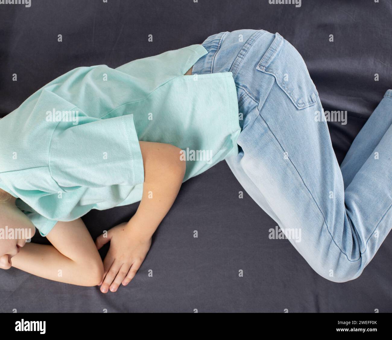 Ein kleines Mädchen liegt auf dem Bett und fühlt sich unwohl. Bauchschmerzen und Hypochondrium. Erkrankungen der Leber und Gallenblase bei Kindern, Cholecystit Stockfoto