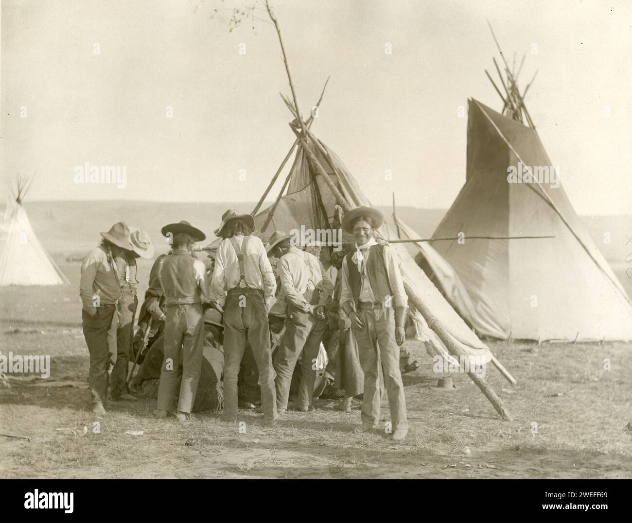 Indische Männer versammeln sich in der Nähe von Tipi im Flathead Reservation, um andere beim Spielen des Glücksspiels zu sehen, Montana, 8.01.1909. Foto: National Archives and Records Administration Stockfoto