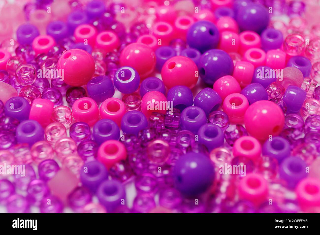 Nahaufnahme von violetten und rosafarbenen Perlen in verschiedenen Größen Stockfoto