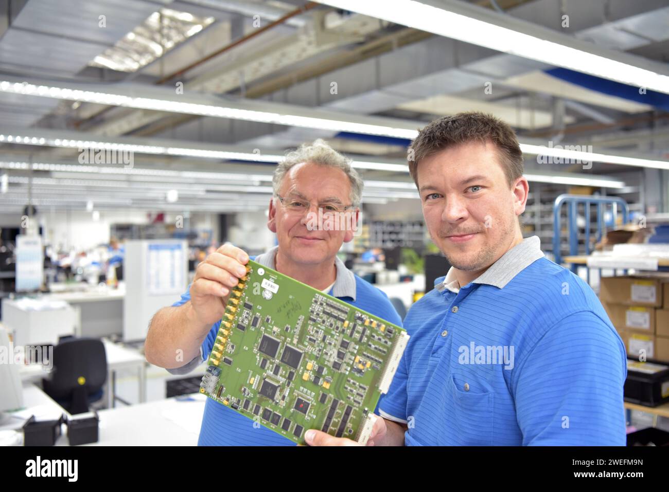Arbeiten in einer Mikroelektronikfabrik - Montage und Löten von Bauteilen - Gruppe von Mitarbeitern im Team Stockfoto