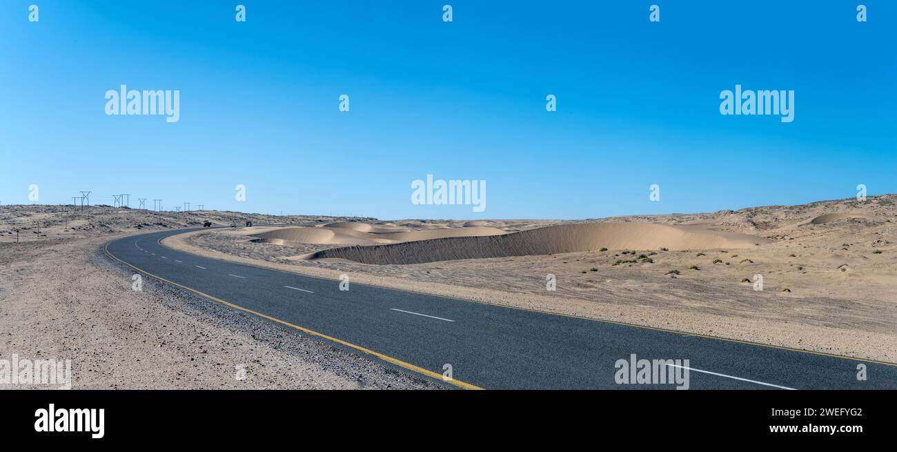 Landschaft mit Sanddünen und Teerstraße B4 in der Wüste Sperrgebiet, aufgenommen im hellen Spätfrühlingslicht bei Luderitz, Namibia, Afrika Stockfoto