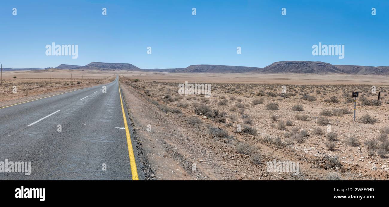 Landschaft mit der B4-Teerstraße in der Wüste, aufgenommen im hellen Licht des späten Frühlings westlich von Goageb, Namibia, Afrika Stockfoto