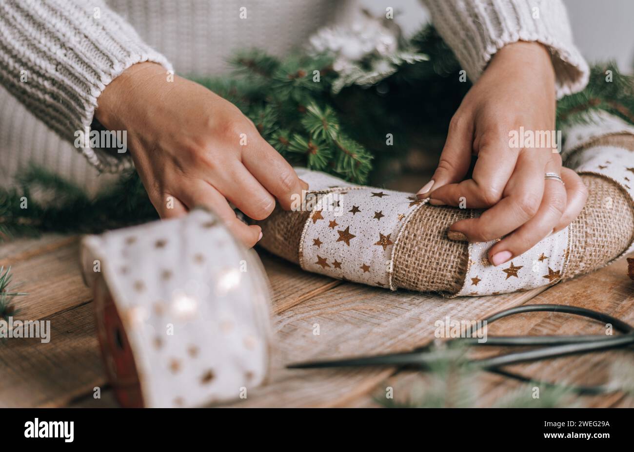 Frau macht schönen weihnachtskranz auf rustikalem Holztisch Stockfoto