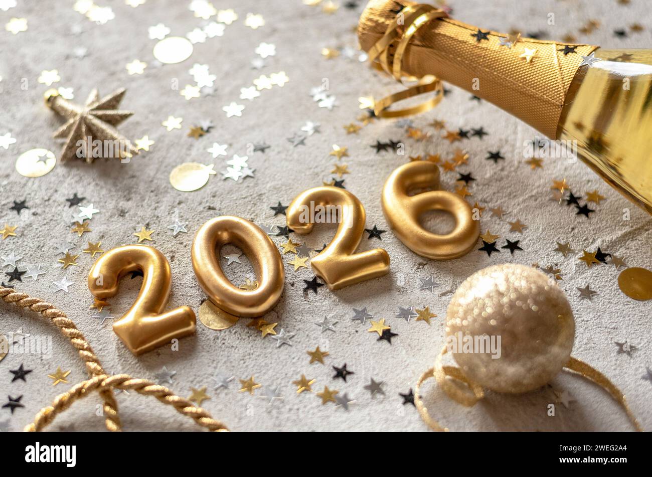 Goldene Farbpalette mit Ziffern für das neue Jahr 2026, umgeben von Konfetti und Dekorationen. Stockfoto