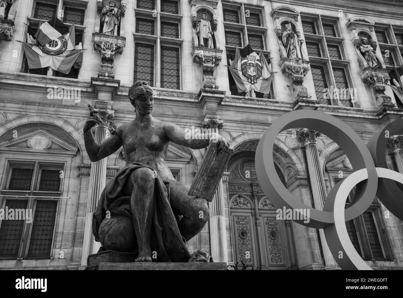 Paris, Frankreich - 21. Februar 2023: Olympische Sommerspiele 2024 in Paris. Olympia-Ringe in der Nähe des Hotels de Ville und der Frauenstatue. Frauen im Sport. Schwarzweiß Stockfoto