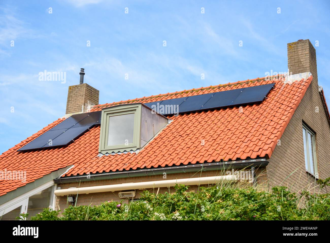 Solarpaneele zur Stromerzeugung auf dem Dach eines modernen Backsteinhauses Stockfoto