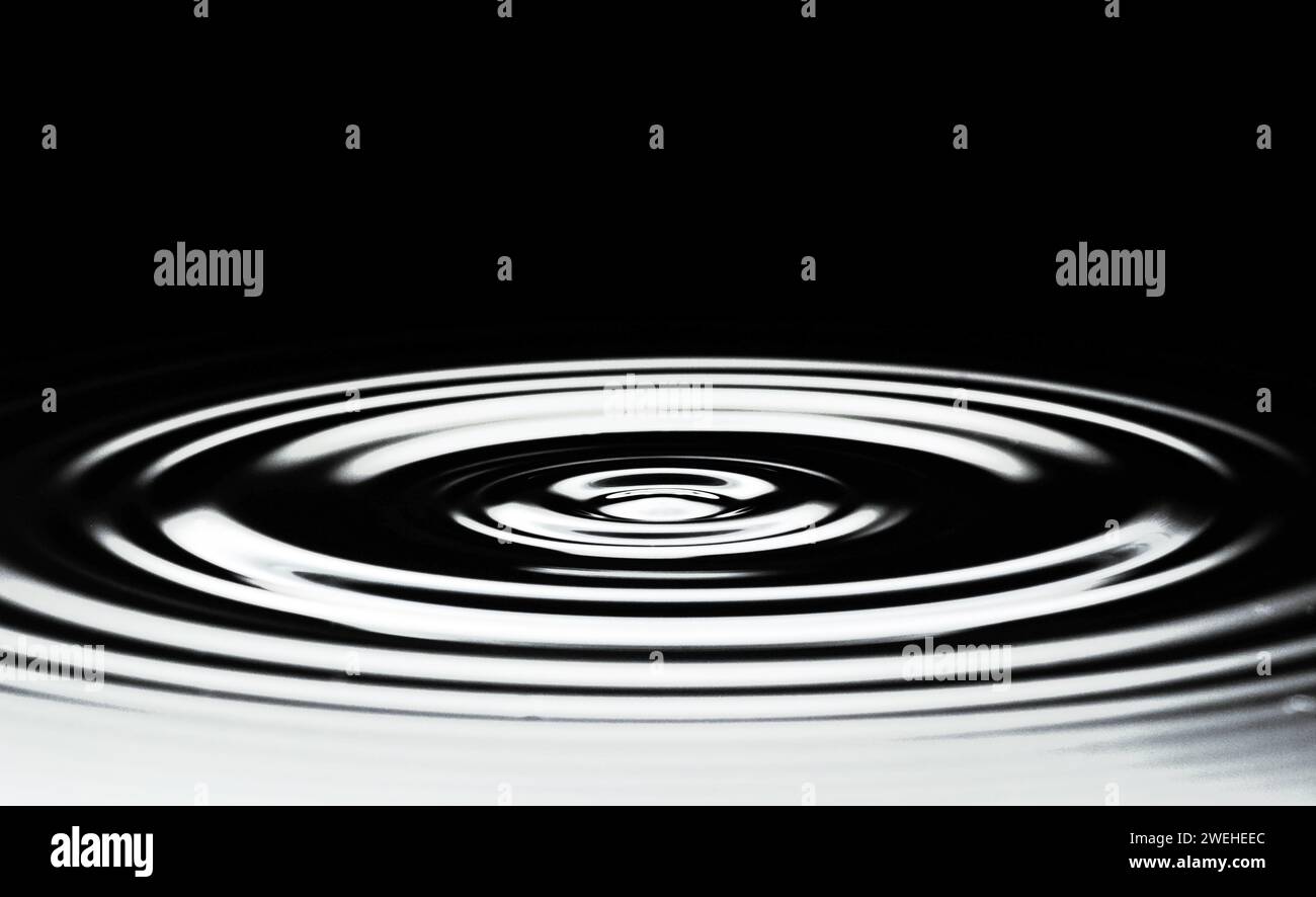 Schwarze Wasseroberfläche mit kreisförmigen Wellen Stockfoto