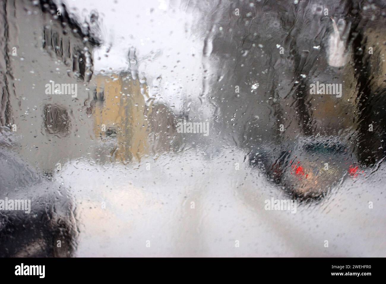 Verschwommener Blick durch die nasse Windschutzscheibe eines Autos im Winter bei Schneefall Stockfoto