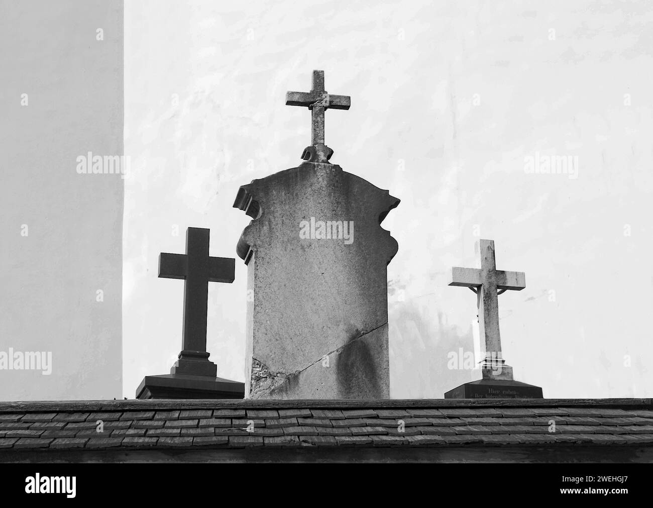 Alte Grabsteine mit Kreuzen an einer katholischen Kirche bei Garmisch-Partenkirchen in Bayern Stockfoto