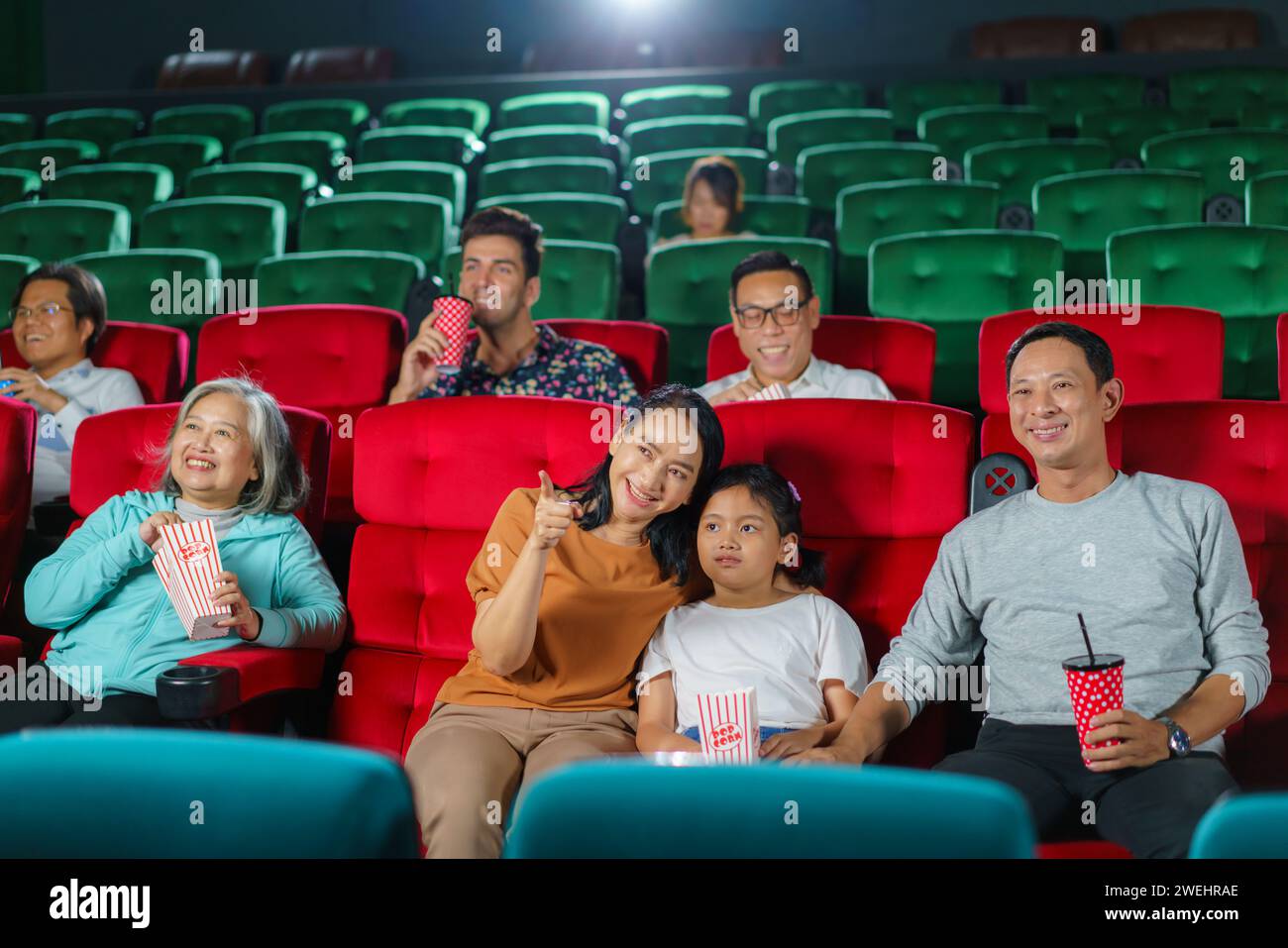 Asiatische Eltern und ihr Kind sehen sich gerne einen Film an, genießen Popcorn zusammen im Kino, gemeinsames Lachen, Binden und die einfachen Freuden eines D Stockfoto