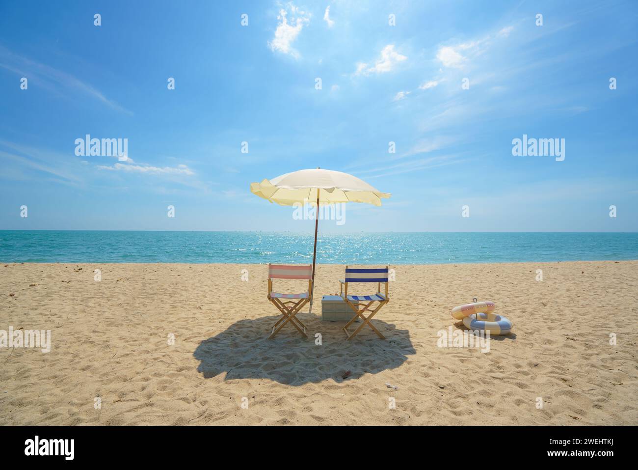 Sessel und Sonnenschirm, perfekt an einem ruhigen Strand gelegen, laden zum Entspannen ein, um die Essenz der Ruhe am Meer und das Versprechen einer friedlichen Esca einzufangen Stockfoto