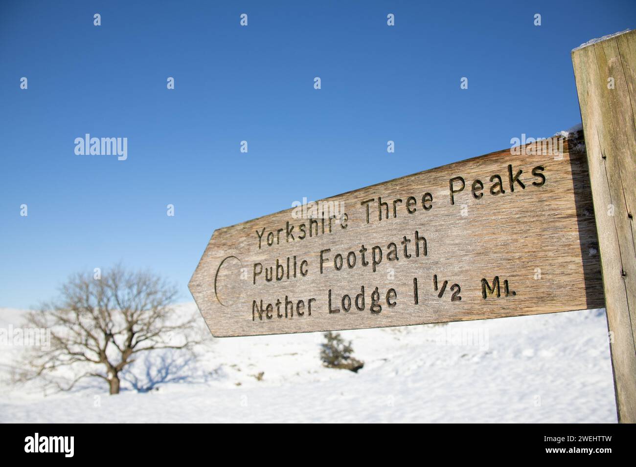 Ein hölzernes Schild für die Yorkshire Three Peaks, den öffentlichen Fußweg und die Nether Lodge zwischen Pen-y-ghent und Whernside in den Yorkshire Dales im Winter. Stockfoto