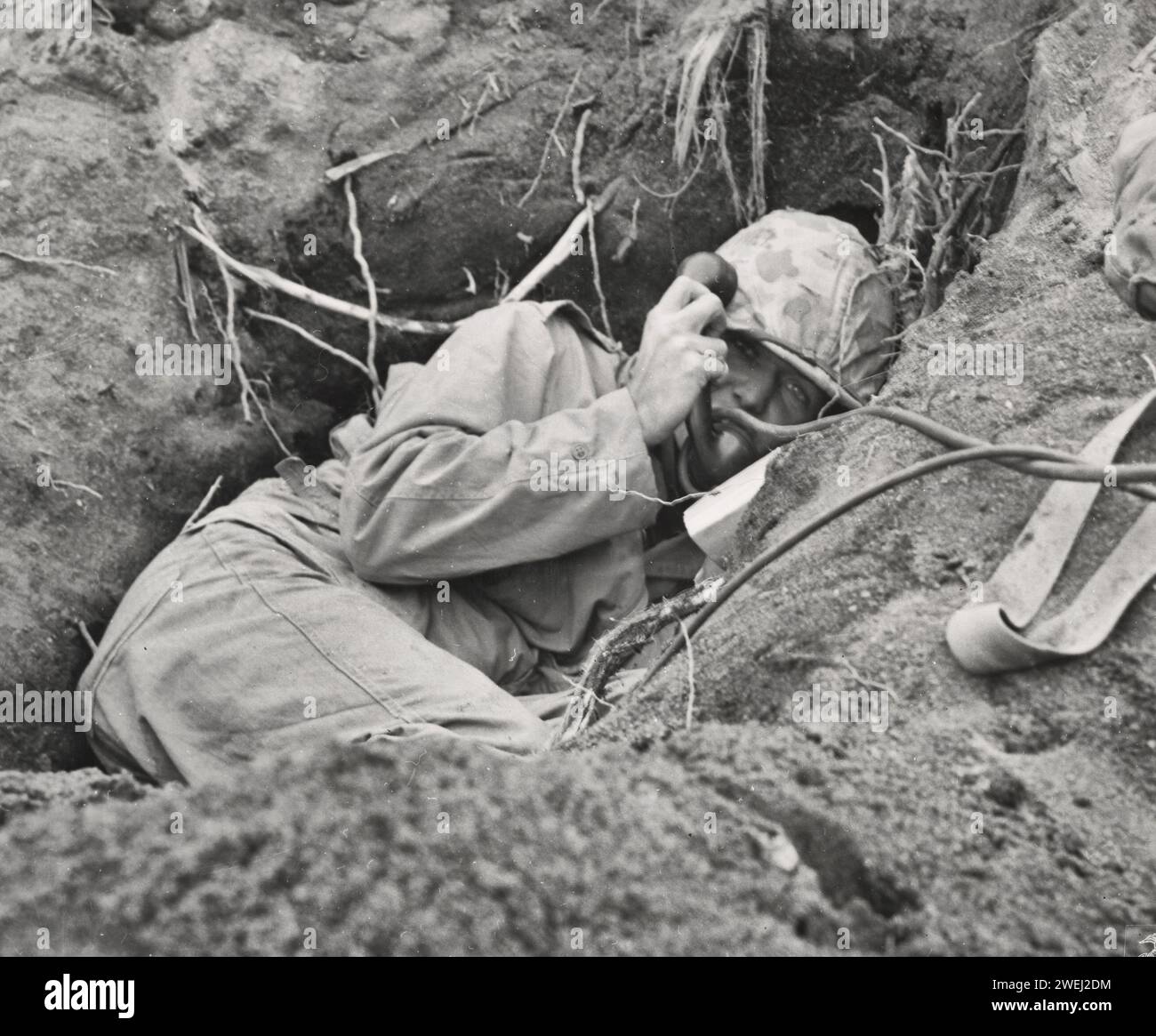 Iwo Jima Phone Booth – ein Marine-Kommandant, der in seinem Fuchsloch am Rande der Motoyama-Landebahn auf Iwo Jima gegraben wurde, ruft zur Artillerieunterstützung auf, um die feindlichen Mörser, die den Vorstoß von Leatherneck verlangsamen, zum Schweigen zu bringen - 1945 Stockfoto