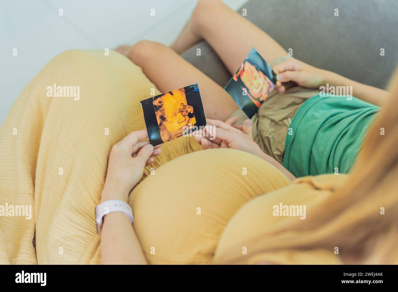 Die werdende Mutter teilt zärtlich die Freude ihres ungeborenen Babys mit ihrem Sohn und zeigt ihm herzerwärmende Ultraschallfotos von seinem bald ankommenden kleinen Kind Stockfoto