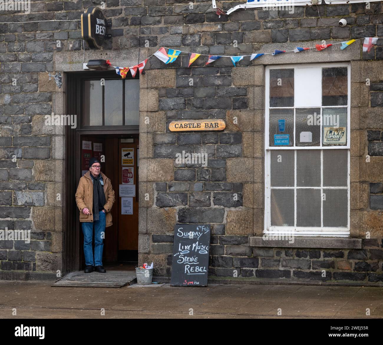25. Januar 2024. Banff, Aberdeenshire, Schottland. Das ist ein Mann, der in der Tür der Castle Bar in der High Street steht und eine Zigarette raucht. Stockfoto