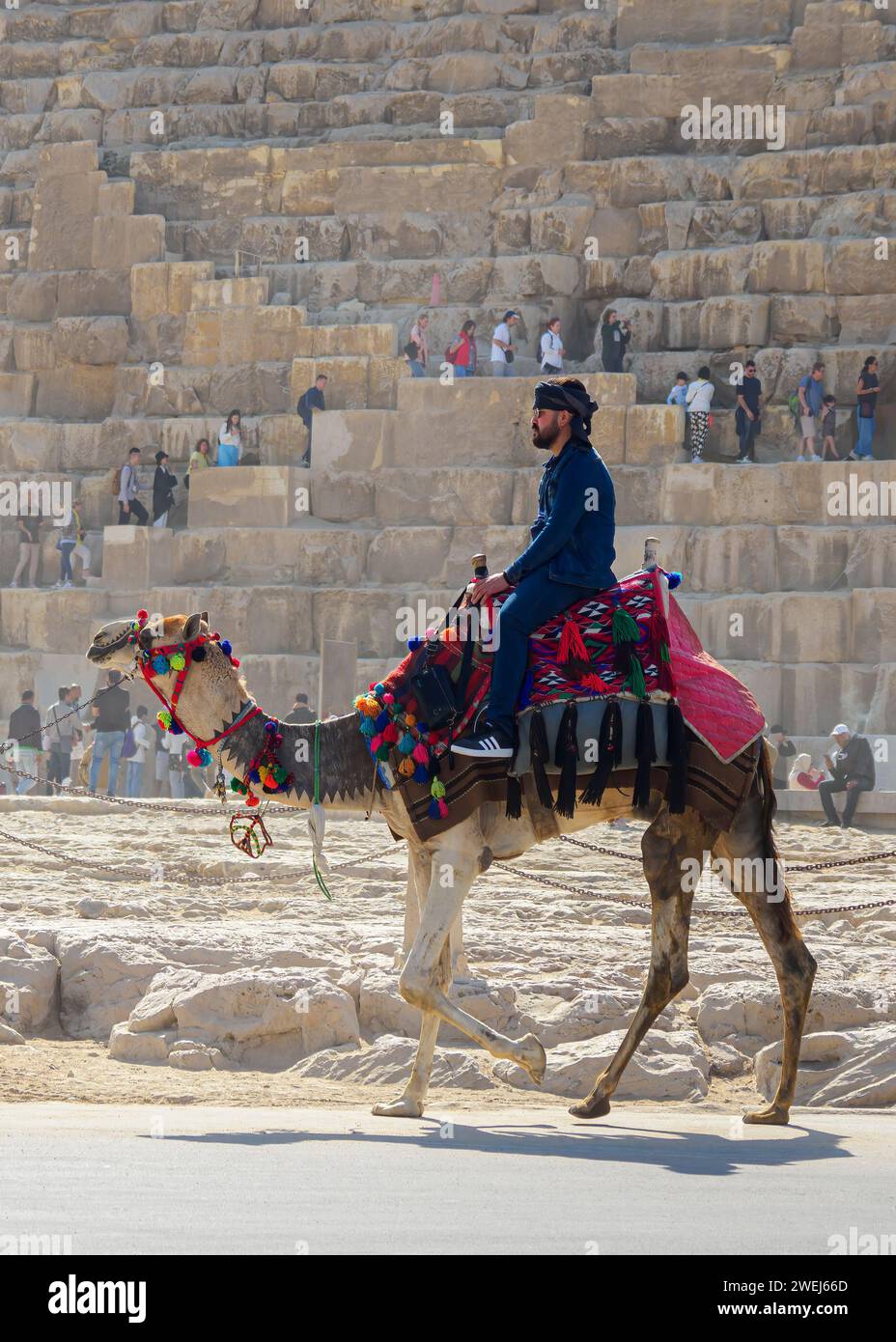 Touristen auf einem Kamelritt vor der Großen Pyramide von Gizeh, dem ältesten der sieben Weltwunder, Kairo, Ägypten. Stockfoto