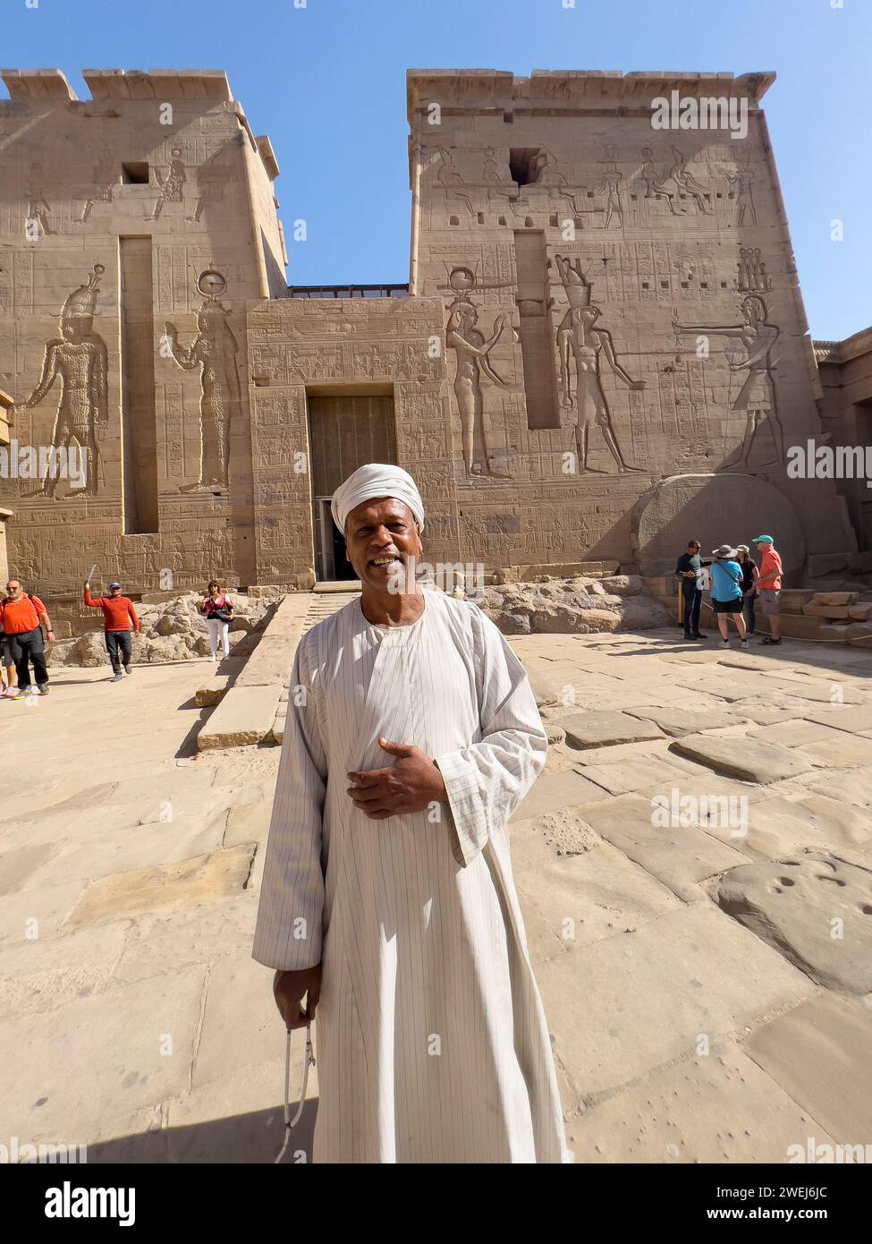 Ägyptischer Mann, der vor dem Philae-Tempelkomplex, dem Isis-Tempel, steht, derzeit auf der Insel Agilkia, Ägypten. Stockfoto