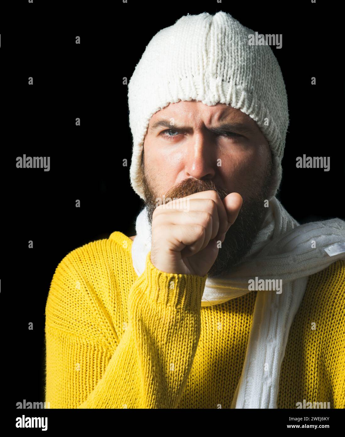 Gutaussehender Kerl mit Halsschmerzen und Husten in die Faust. Ungesunder Mann in Schal gewickelt haben Husten als Symptom für Influenza, Erkältung oder Bronchitis Stockfoto