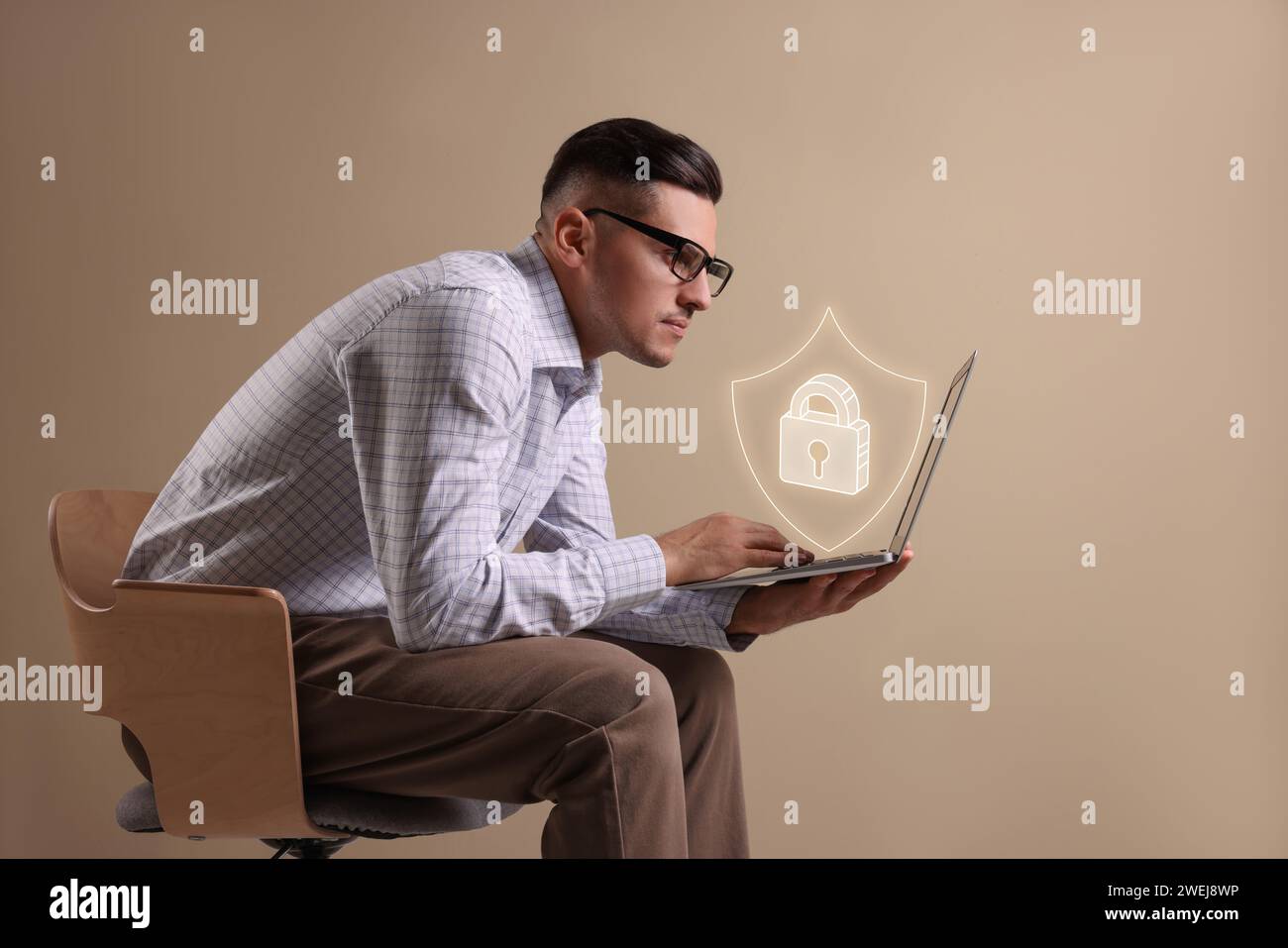 Datenschutz. Mann, der in Innenräumen ein Notebook benutzt. Abbildung: Abschirmung mit Vorhängeschloss über dem Gerät Stockfoto