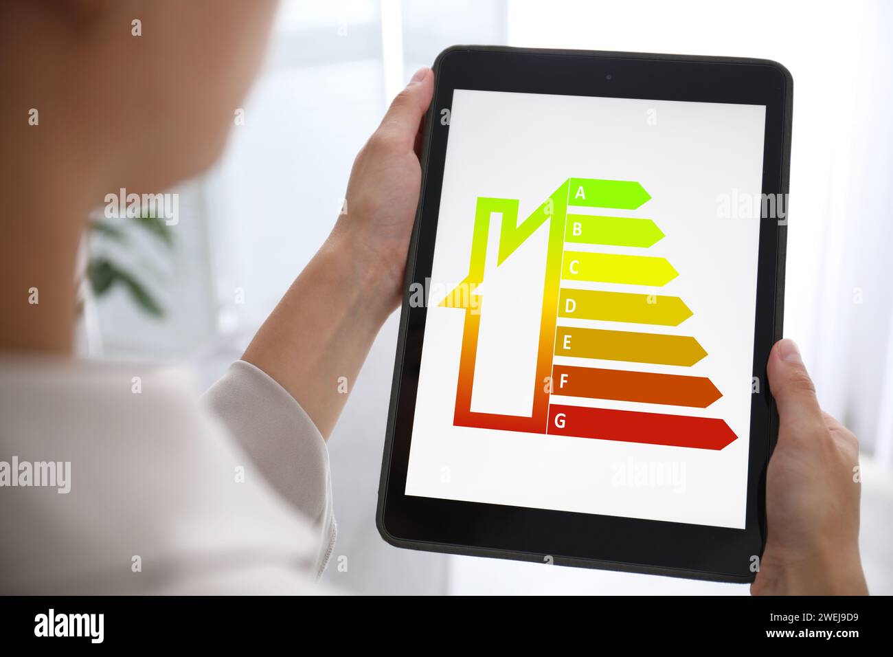 Energieeffizienz. Frau, die ein Tablet mit farbenfroher Bewertung in Innenräumen verwendet, Nahaufnahme Stockfoto