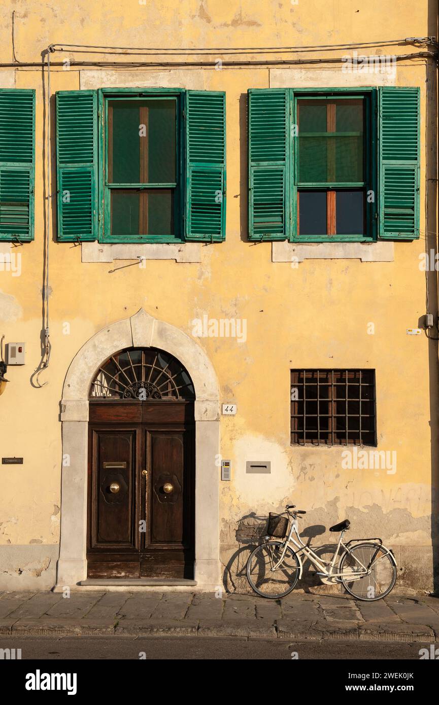 Fahrrad vor der Gebäudefassade mit gelben Wänden und grünen Fensterläden, Pisa, Toskana, Italien Stockfoto
