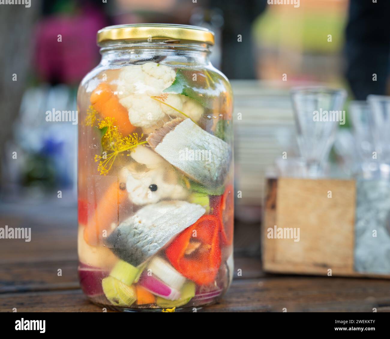 Salzen von Gemüse in Glasgläsern zur Langzeitlagerung. Vielfalt fermentiertes buntes Gemüse und Fisch im Glasgefäß. Selektiver Fokus. Stockfoto