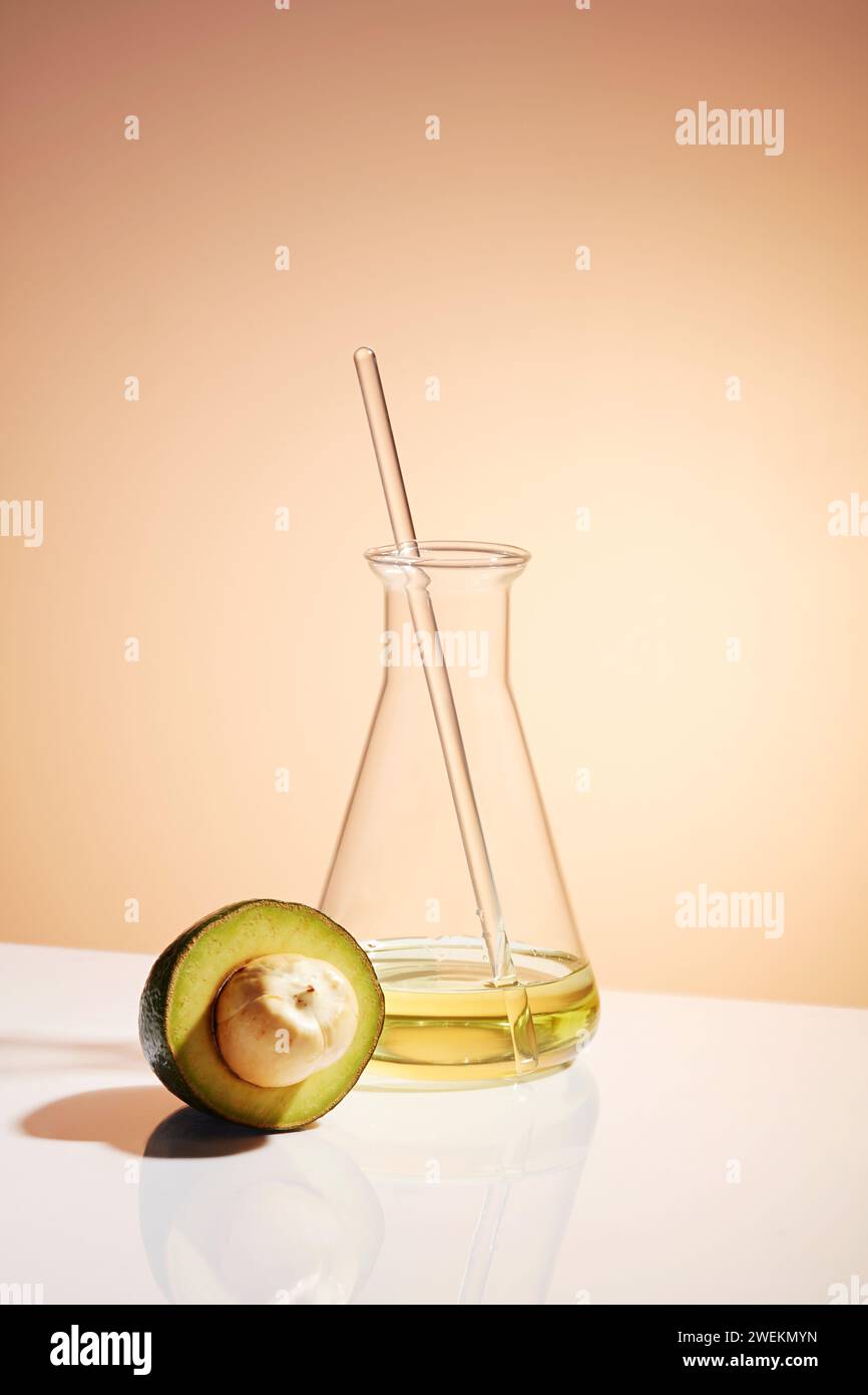 Erlenmeyerkolben mit flüssiger und frischer Avocadoscheibe auf farbigem Hintergrund. Avocados sind eine Frucht mit Kohlenhydraten und gesunden Fetten, die p Stockfoto