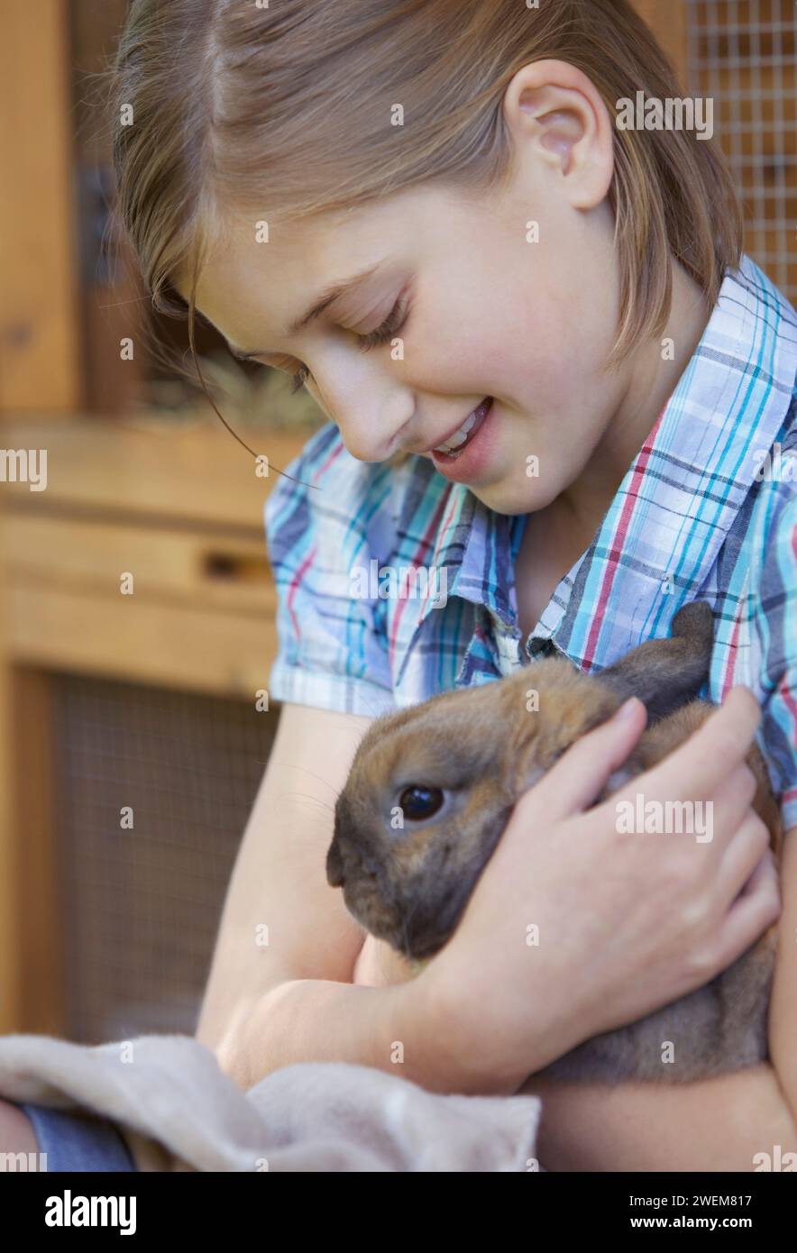 Süßes Mädchen, das braunes Kaninchen hält Stockfoto