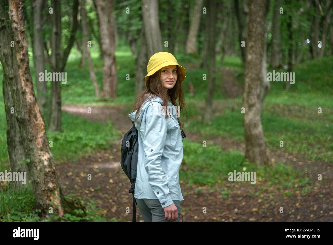 Junge Frau, die an einem sonnigen Tag in einem Wald spaziert Stockfoto