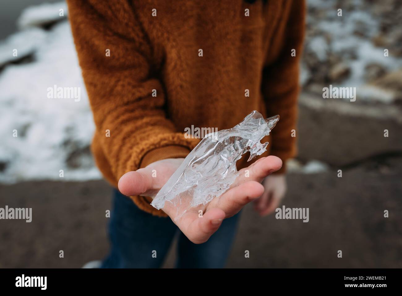 Kind, das gefrorene Eisbildung am Uferufer hält Stockfoto