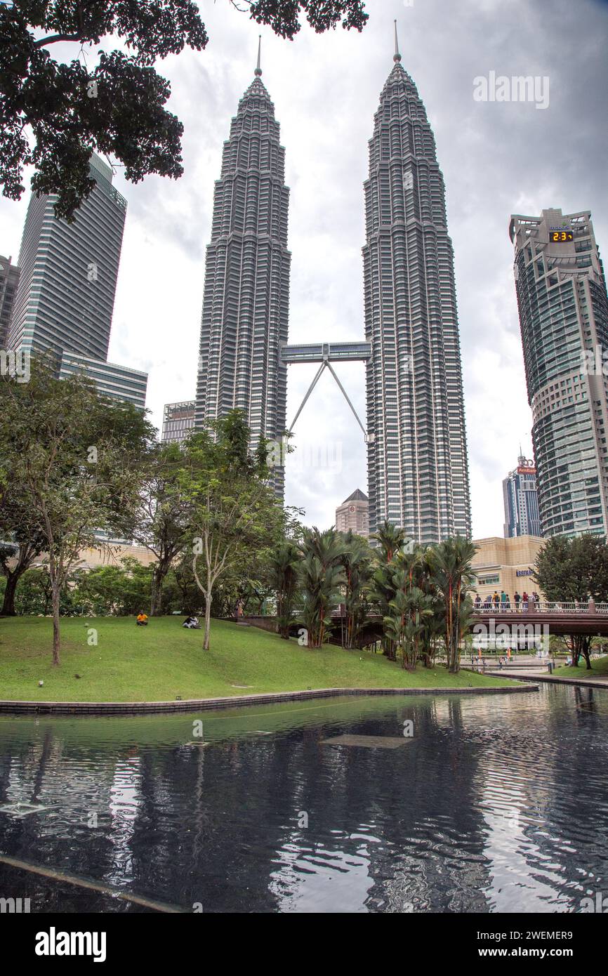 Leute im Park, unter den Petronas Towers während des bewölkten Tages Stockfoto