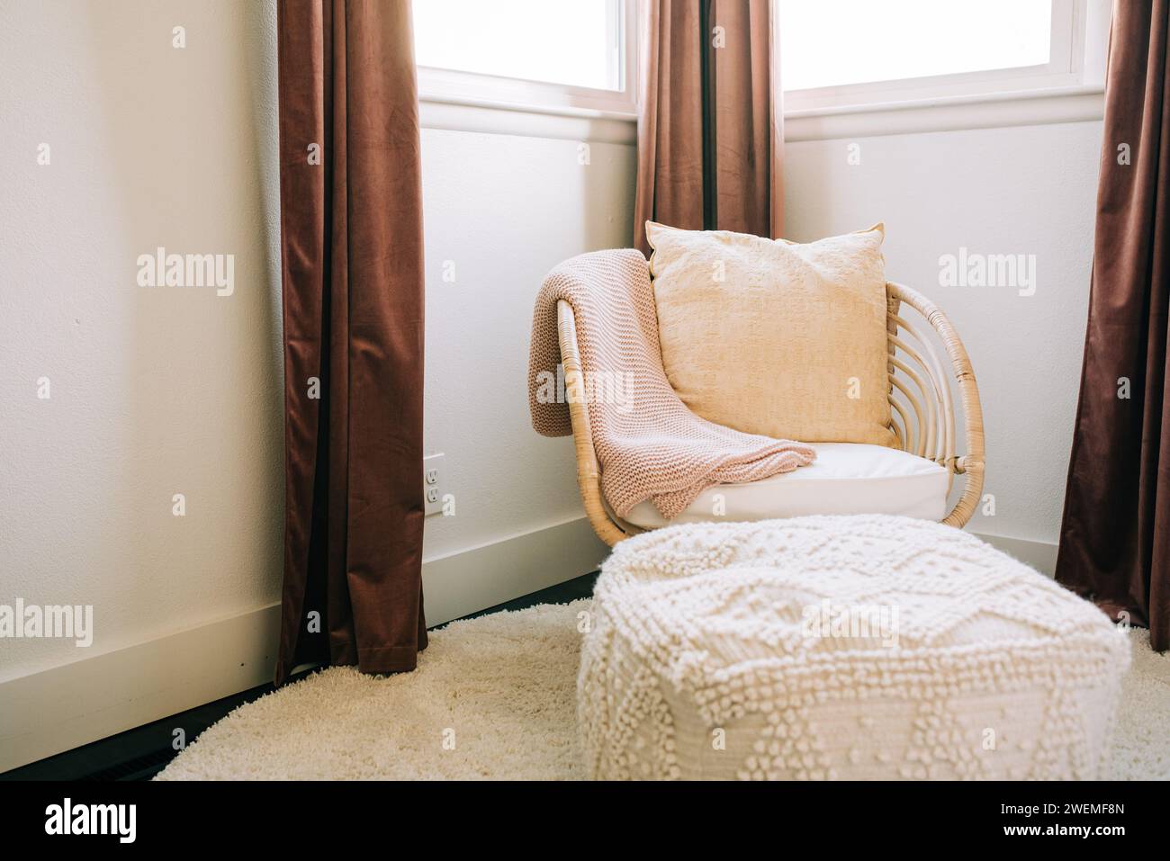 Boho-Stuhl und Ottomane in einem kleinen Zimmer Stockfoto