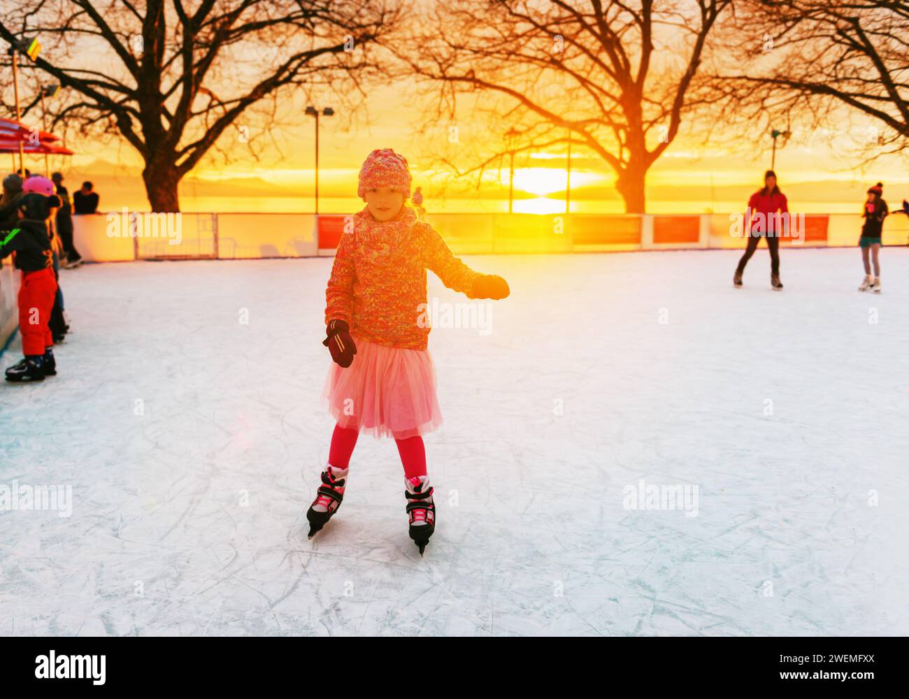 Süßes kleines Mädchen auf der Eislaufbahn in rosa Kleidung Stockfoto