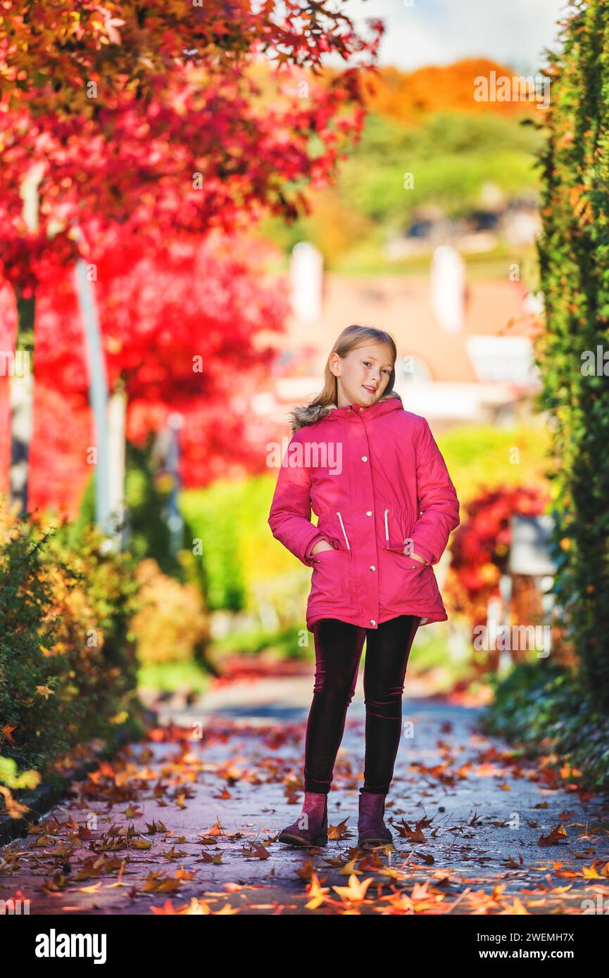 Herbstporträt eines niedlichen kleinen Mädchens mit hellrosa Jacke und Stiefeln Stockfoto
