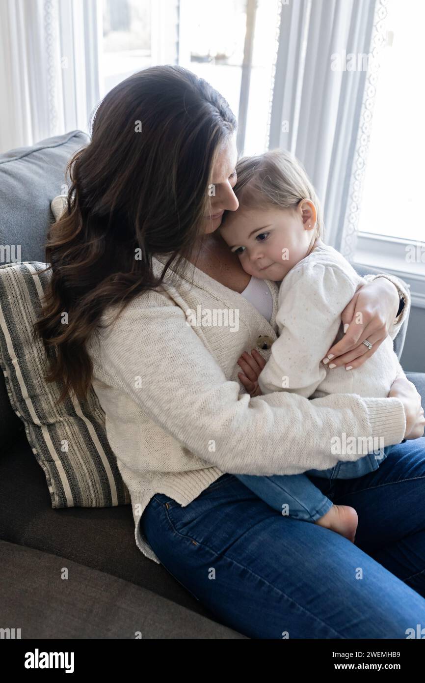 Mutter hält ihr Baby auf der Couch Stockfoto