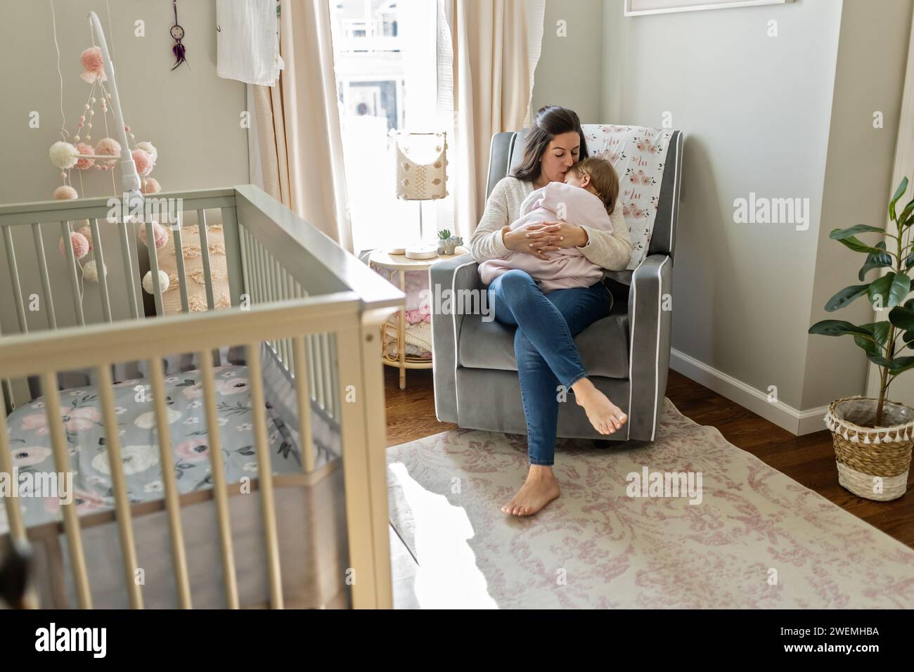 Mutter rockt das Baby im Kinderzimmer Stockfoto