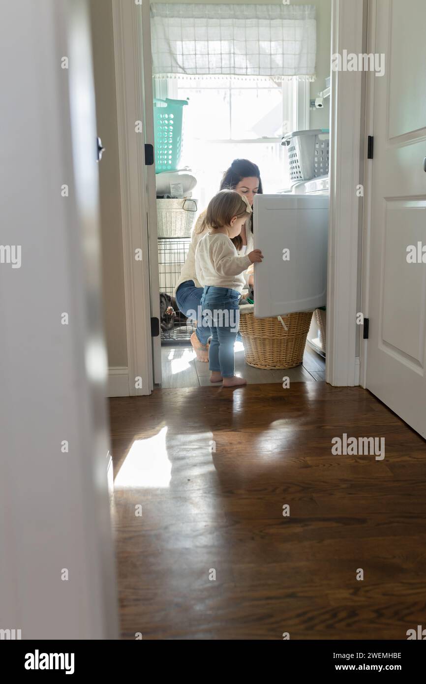 Vertikales Bild von Mama und Kleinkind, die Kleidung aus dem Trockner nehmen Stockfoto