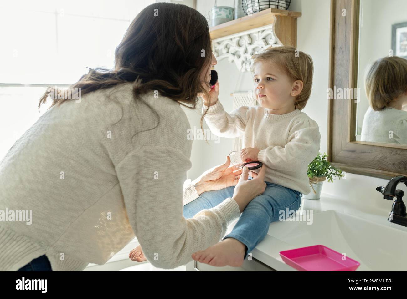 Ein kleines Mädchen, das so tut, als würde sie Mutter schminken Stockfoto