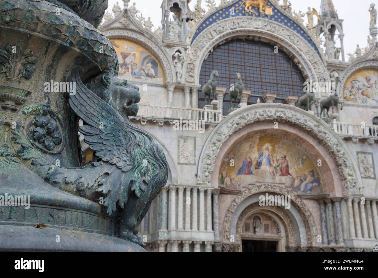 Altes Straßenschmuck mit geflügelten Löwen und Markusdom im Hintergrund, in St. Markplatz, berühmte Touristenattraktion in Venedig, Italien. Stockfoto