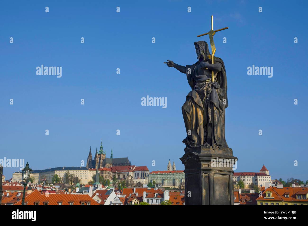 Statue von St. Johannes der Täufer auf der Karlsbrücke, mit Hradcany Castle und St. Vitusdom im Hintergrund, in Prag, Tschechien, sonnig Stockfoto