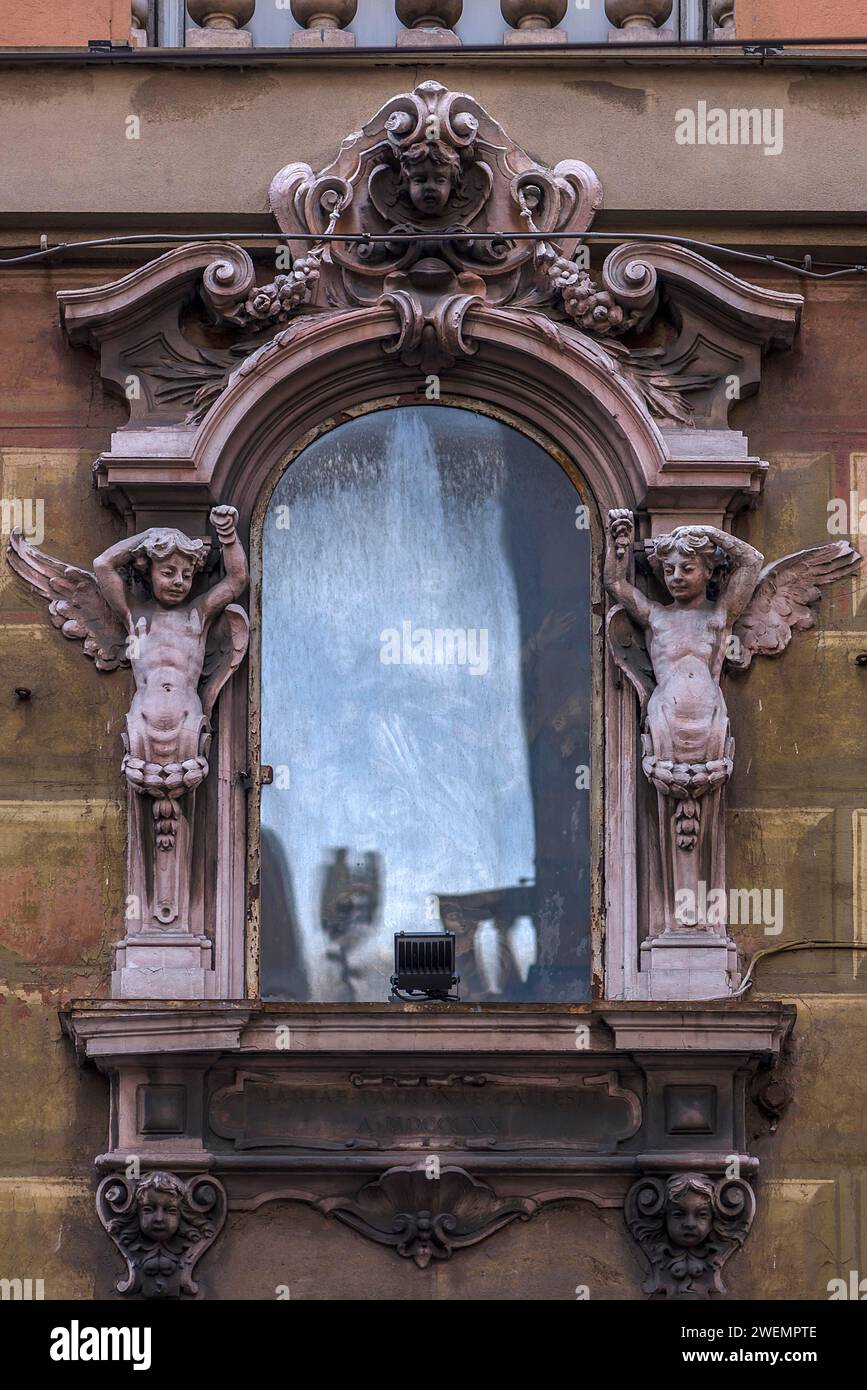 Verblasstes Gemälde eines heiligen mit dekorativem Rahmen mit Engelskulpturen, historisches Zentrum, Genua, Italien Stockfoto