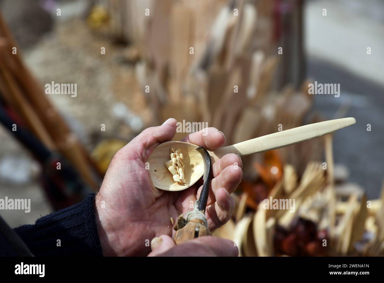 Ein Graveur schnitzt einen Holzlöffel mit einem Meißel an seiner Hand nach traditioneller Methode. Verfahren zur Herstellung eines geschnitzten Holzlöffels. Stockfoto