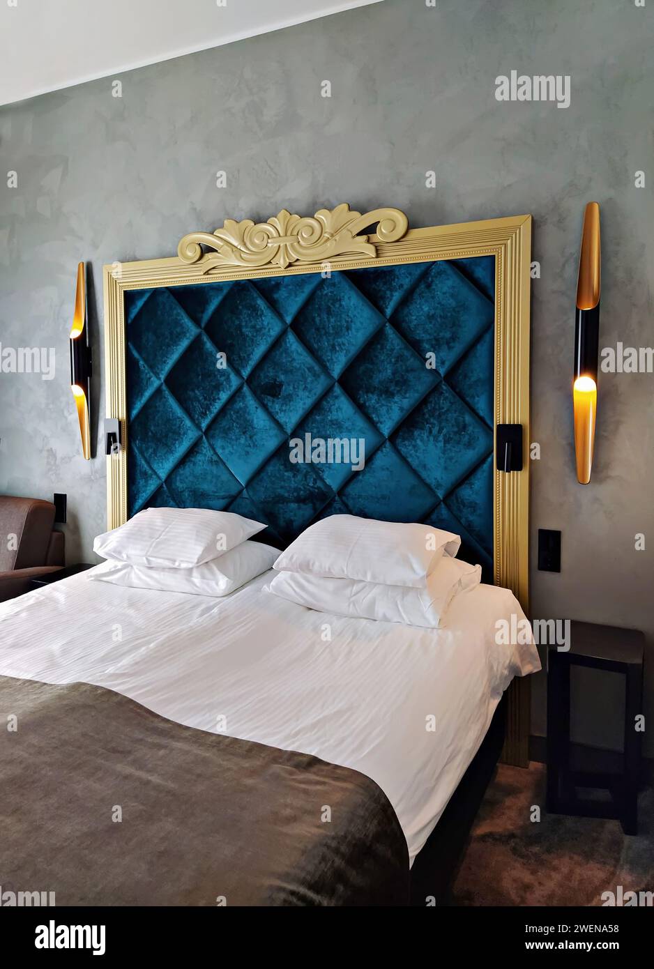 Elegantes Boutique-Hotelzimmer mit modernen Wandlampen und luxuriöser Bettwäsche Stockfoto
