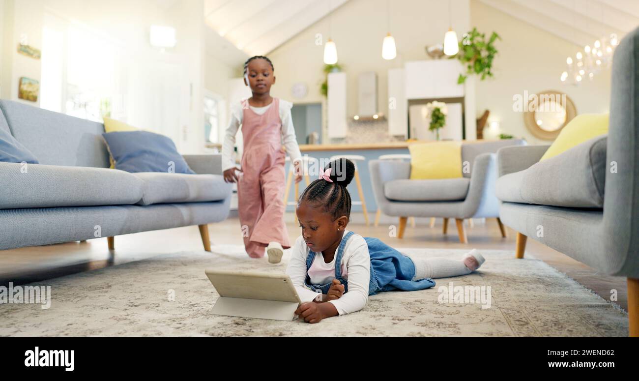 Schwarze Mädchen Kinder auf dem Boden mit Tablet und entspannen, e-learning oder Zeichentrickfilme sehen, Schwestern zu Hause und Bildschirmzeit. Junge weibliche Kinder, streamen Stockfoto