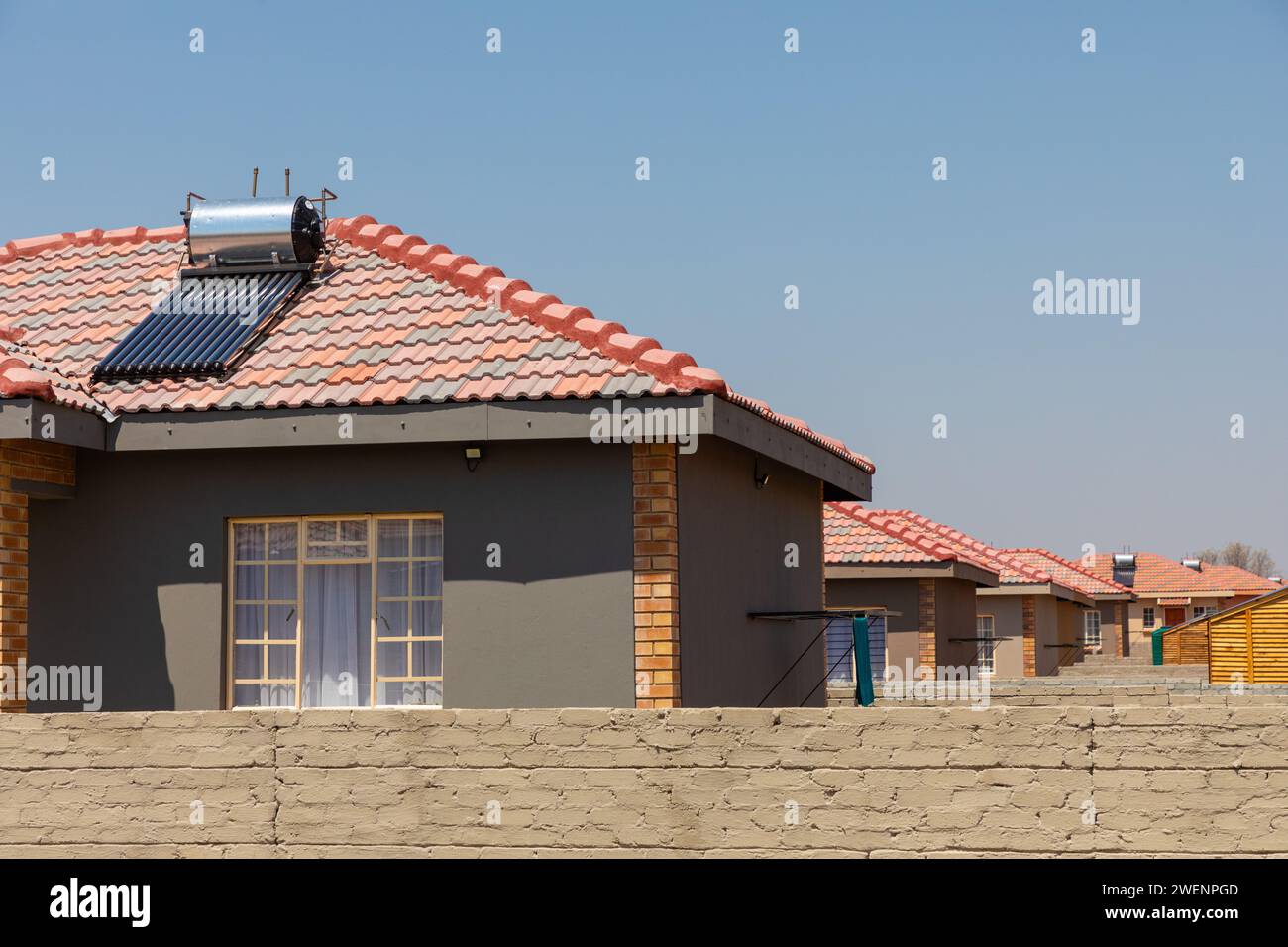 Eine neue Wohnunterteilung mit solarbetriebenen Warmwasserbereitern auf den Dächern in Mogwase, Nordwesten, Südafrika. Stockfoto